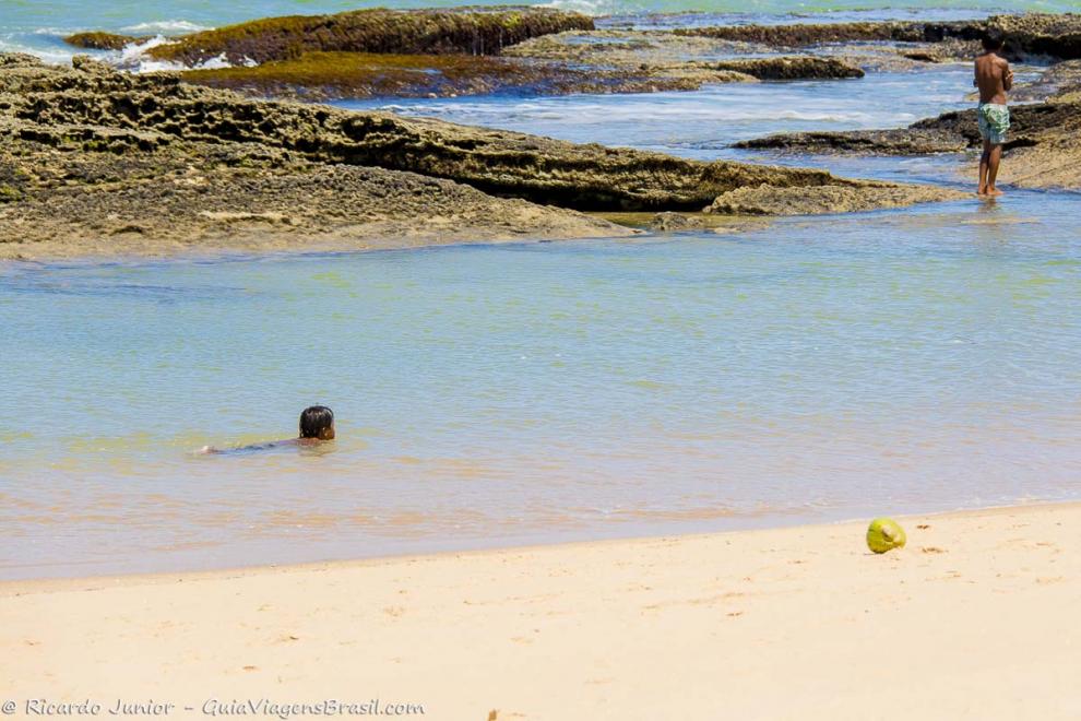 Imagem de uma cirança nas águas claras da piscina natural da Praia de Caraiva.